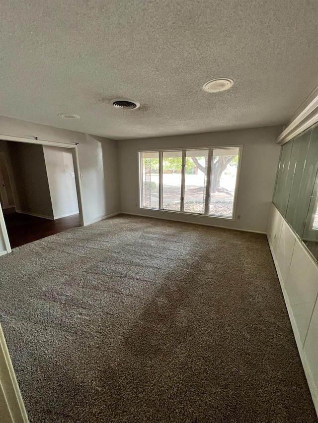 carpeted empty room featuring a textured ceiling