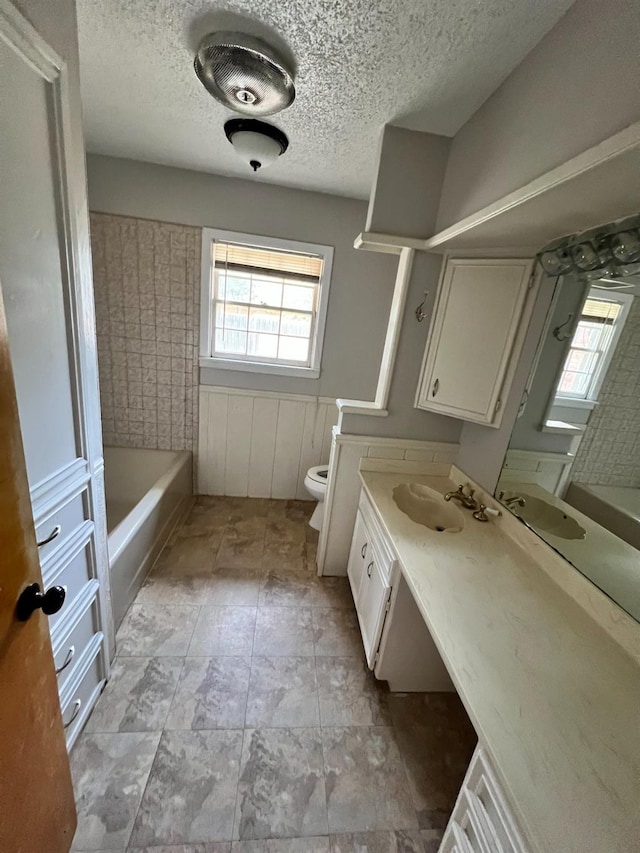 bathroom with vanity, toilet, and a textured ceiling