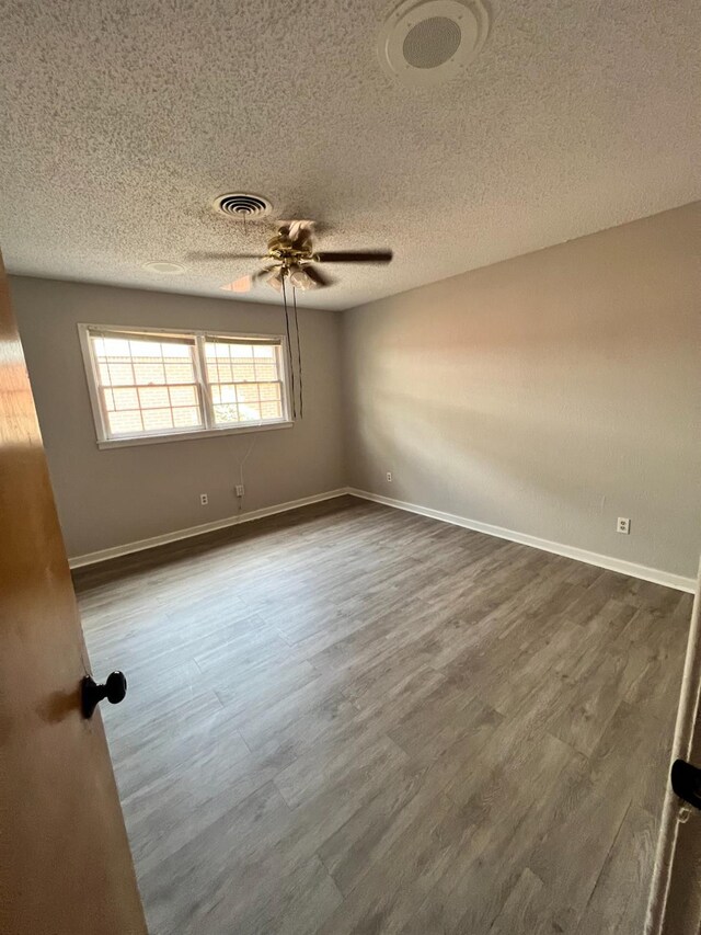 spare room with ceiling fan, a textured ceiling, and dark hardwood / wood-style flooring