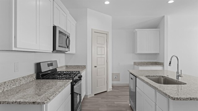 kitchen featuring sink, light hardwood / wood-style flooring, stainless steel appliances, light stone countertops, and white cabinets