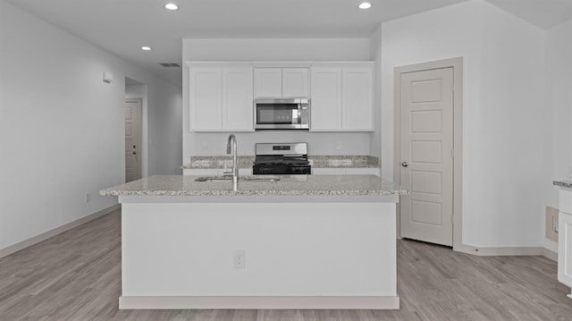 kitchen featuring sink, appliances with stainless steel finishes, a kitchen island with sink, light hardwood / wood-style floors, and white cabinets