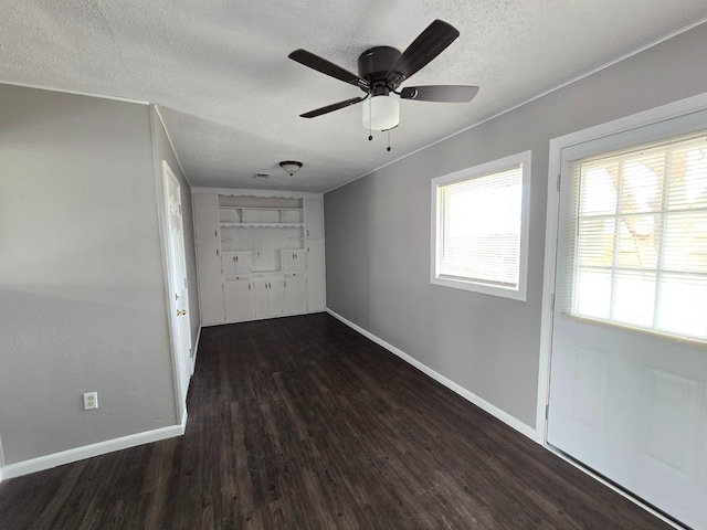 unfurnished room featuring dark hardwood / wood-style flooring, ceiling fan, and a textured ceiling