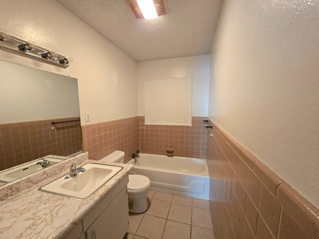 bathroom with a tub, vanity, toilet, tile patterned floors, and a textured ceiling