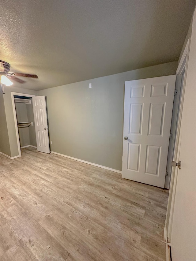 unfurnished bedroom featuring ceiling fan, light hardwood / wood-style floors, a closet, and a textured ceiling