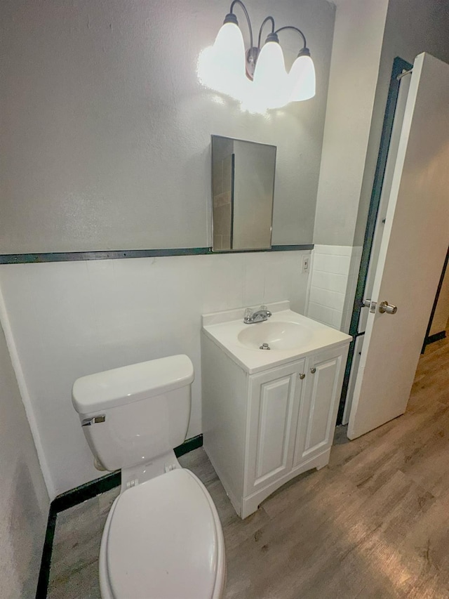 bathroom featuring wood-type flooring, toilet, and vanity