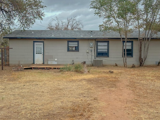 rear view of house featuring central AC and a lawn