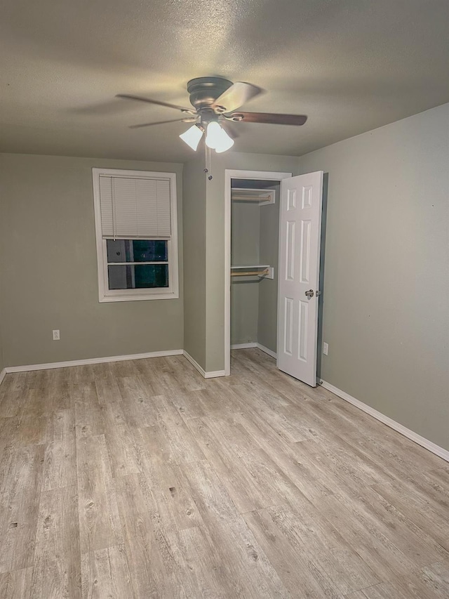 unfurnished bedroom featuring ceiling fan, a closet, light hardwood / wood-style floors, and a textured ceiling