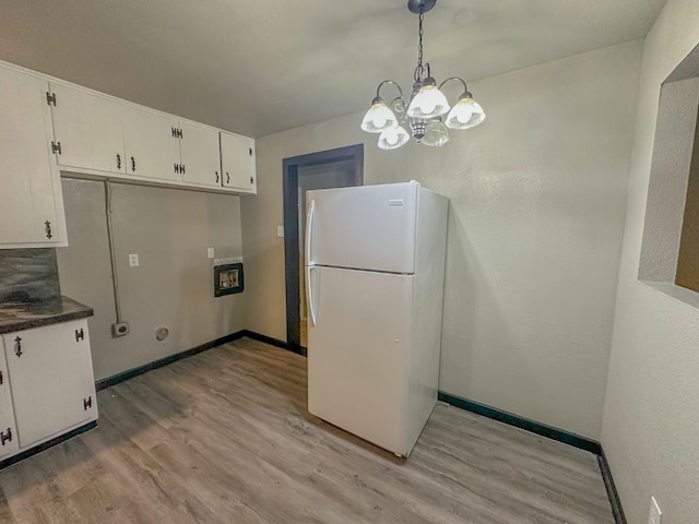 kitchen with white cabinetry, light hardwood / wood-style floors, hanging light fixtures, and white fridge