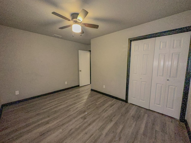 unfurnished bedroom featuring hardwood / wood-style floors, a textured ceiling, ceiling fan, and a closet