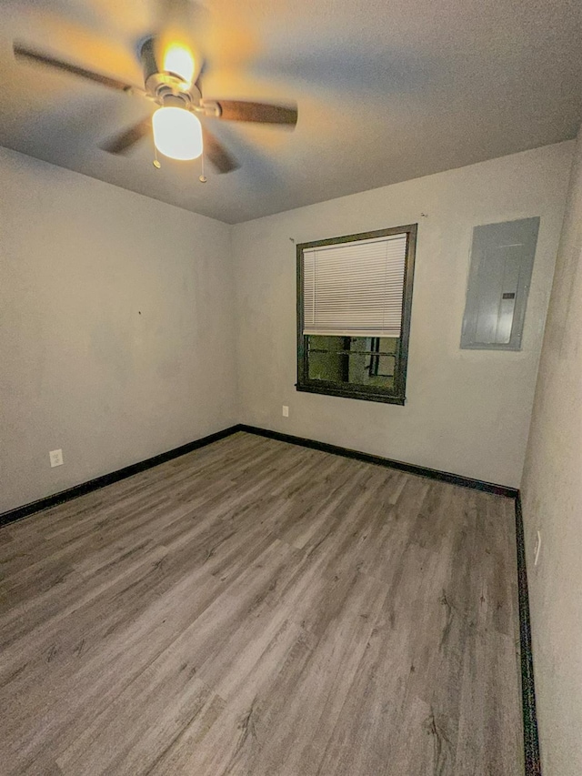 spare room featuring ceiling fan, wood-type flooring, and electric panel