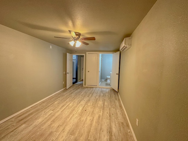 unfurnished room featuring ceiling fan, light hardwood / wood-style floors, a textured ceiling, and an AC wall unit