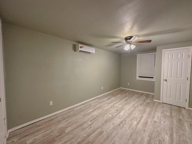 interior space featuring ceiling fan, light wood-type flooring, a textured ceiling, and a wall unit AC