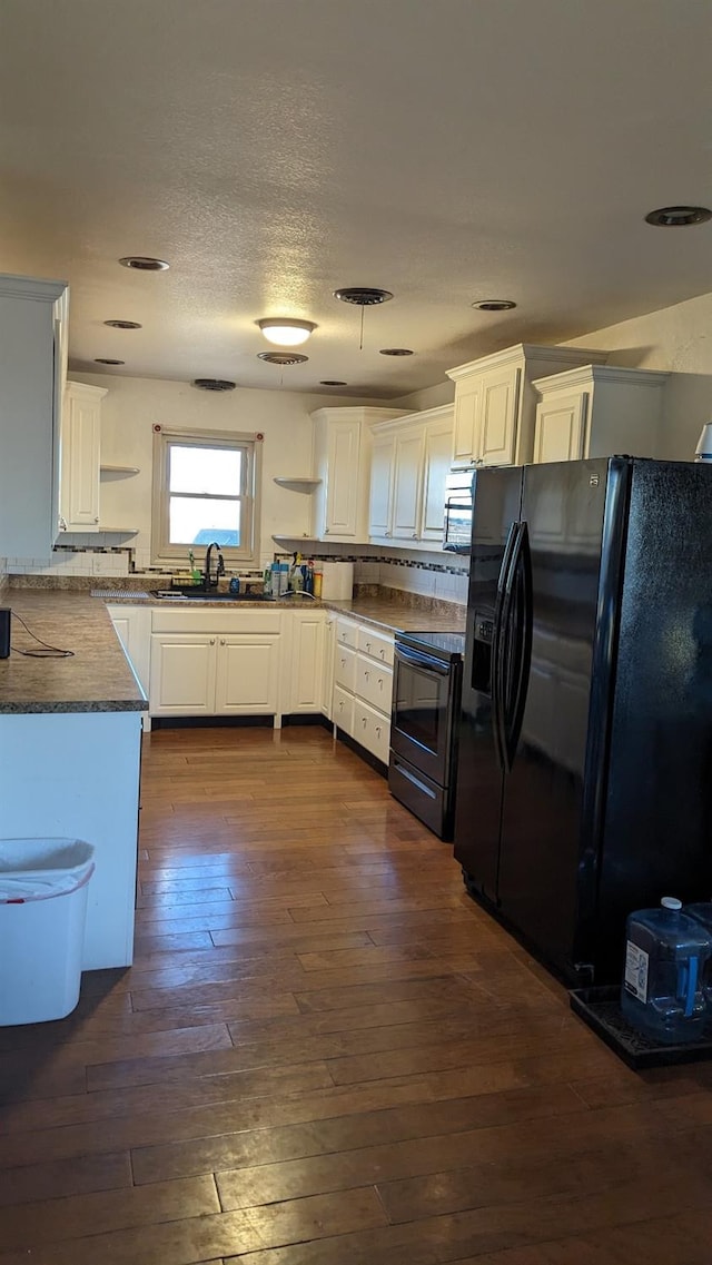 kitchen with white cabinetry, black fridge, dark hardwood / wood-style floors, and range with electric cooktop