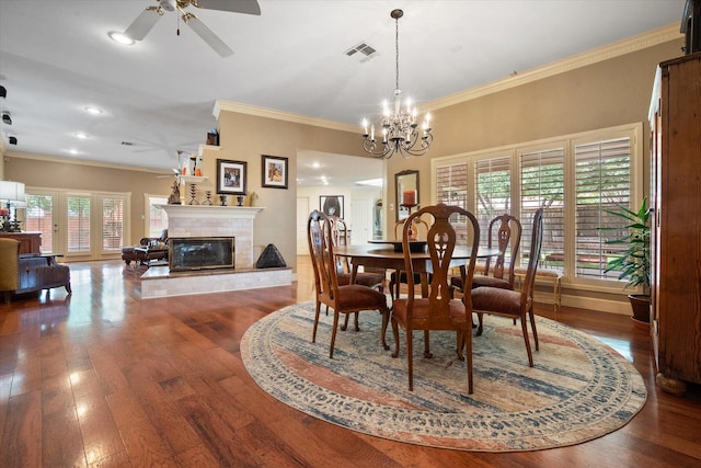 314 York Ave, Lubbock, TX 79416 - dining area with a ceiling fan, a tiled fireplace, ornamental molding, hardwood / wood-style flooring, and a chandelier