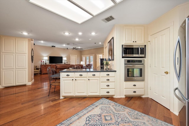 314 York Ave, Lubbock, TX 79416 - kitchen with stainless steel appliances, open floor plan, dark countertops, light wood-style flooring, and a peninsula