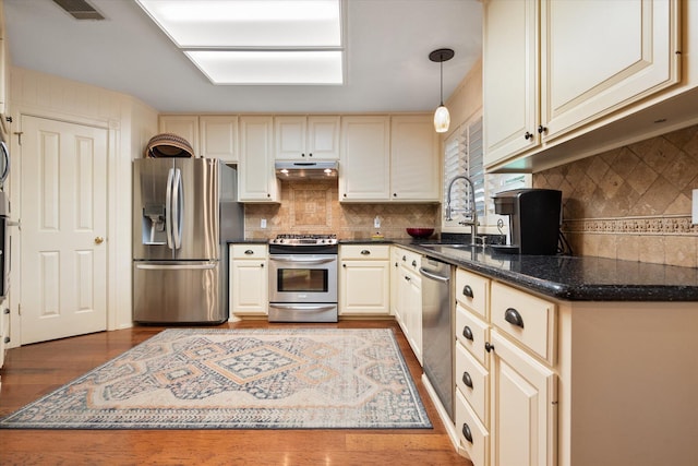 314 York Ave, Lubbock, TX 79416 - kitchen featuring stainless steel appliances, under cabinet range hood, tasteful backsplash, dark wood finished floors, and hanging light fixtures