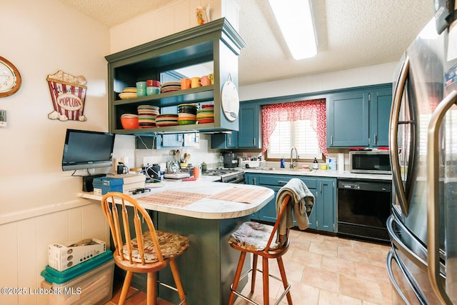 4610 63rd St, Lubbock, TX 79414 - kitchen featuring stainless steel appliances, a peninsula, a kitchen breakfast bar, light countertops, and a textured ceiling