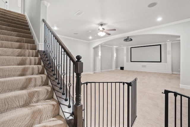 carpeted home theater room featuring ceiling fan and ornamental molding