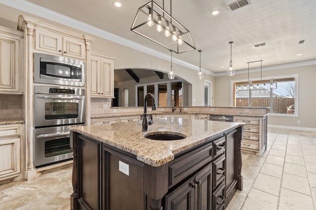 kitchen featuring sink, light stone counters, dark brown cabinets, pendant lighting, and backsplash