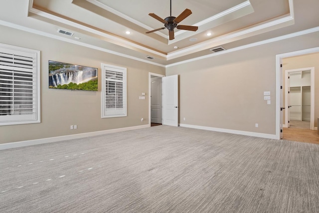 empty room featuring crown molding, ceiling fan, a raised ceiling, and light carpet