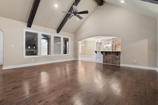 unfurnished living room with beam ceiling, ceiling fan with notable chandelier, high vaulted ceiling, and dark hardwood / wood-style floors