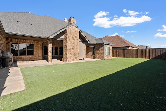 rear view of house with a patio and a lawn