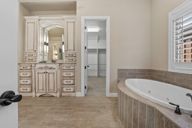 bathroom with vanity, tiled tub, and a wealth of natural light