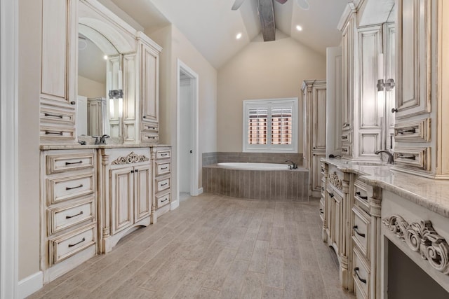 bathroom featuring tiled tub, ceiling fan, hardwood / wood-style floors, vanity, and lofted ceiling with beams