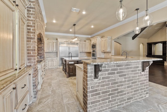 kitchen with a large island, a breakfast bar, built in appliances, and decorative light fixtures