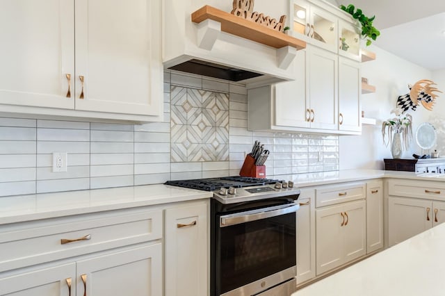 kitchen featuring premium range hood, white cabinetry, backsplash, gas stove, and light stone countertops