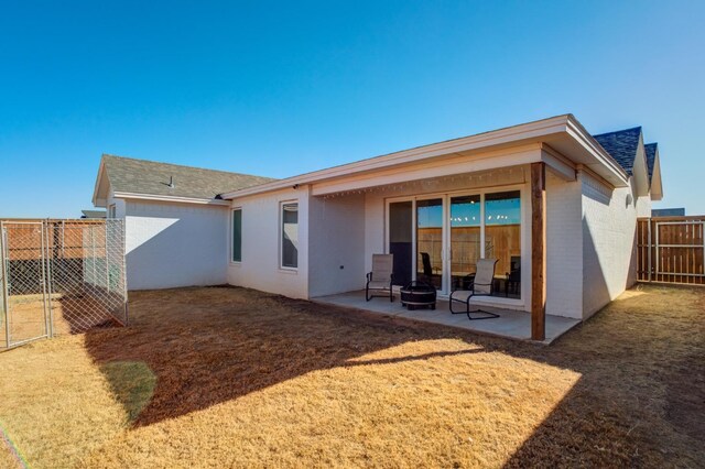 rear view of property with a fire pit and a patio