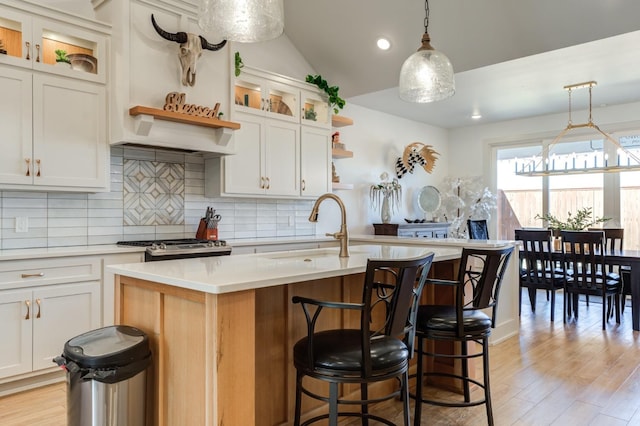 kitchen with pendant lighting, sink, a kitchen island with sink, and white cabinets