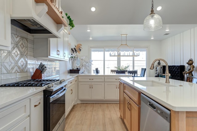 kitchen with appliances with stainless steel finishes, sink, white cabinets, custom exhaust hood, and hanging light fixtures