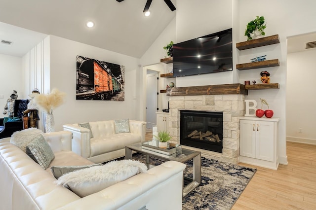 living room featuring ceiling fan, high vaulted ceiling, a fireplace, and light hardwood / wood-style floors