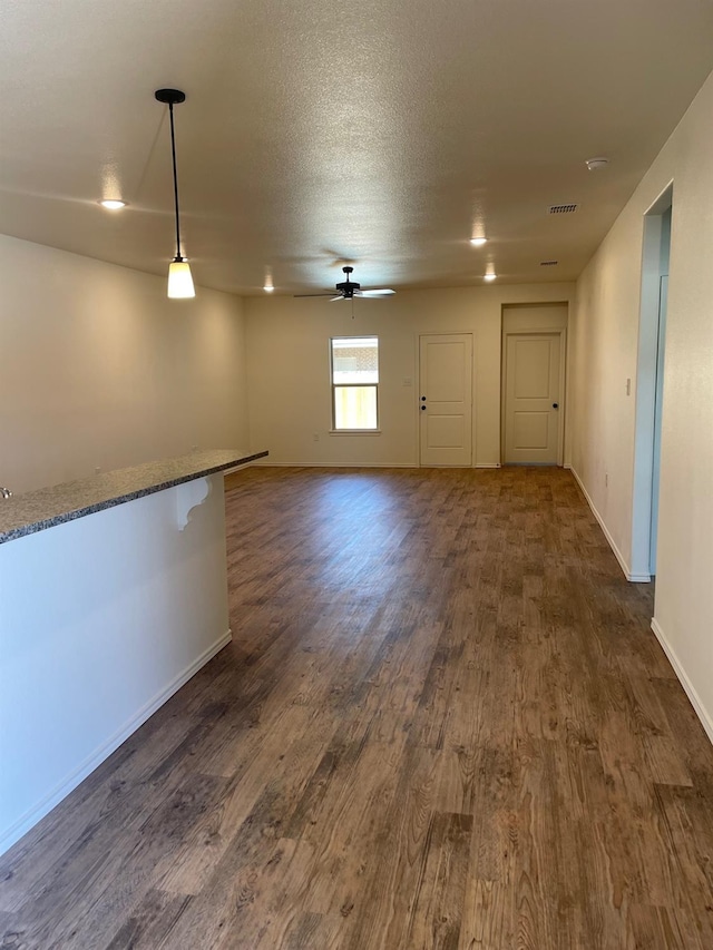 empty room featuring a textured ceiling, dark wood-type flooring, and ceiling fan