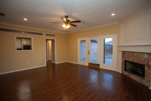 unfurnished living room with a textured ceiling, dark wood-type flooring, a tile fireplace, and ceiling fan