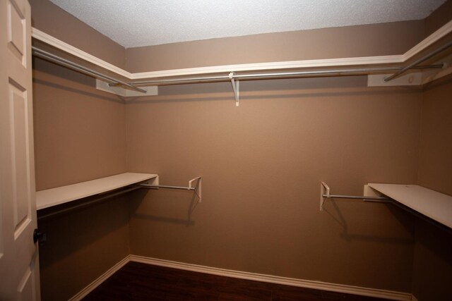 spacious closet featuring dark hardwood / wood-style flooring and built in desk