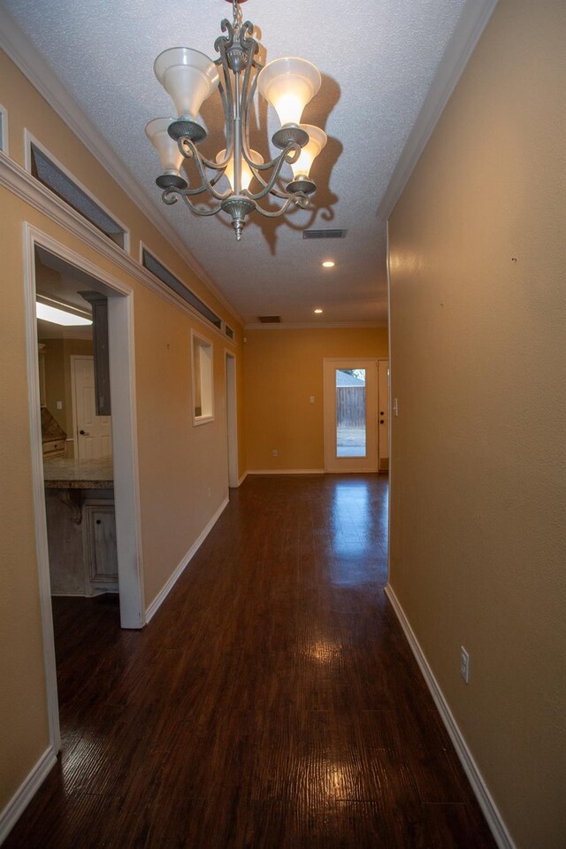 hallway featuring an inviting chandelier, dark hardwood / wood-style floors, a textured ceiling, and crown molding