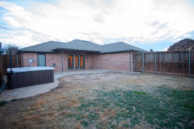 4910 102nd St, Lubbock, TX 79424 - rear view of property featuring a hot tub, a fenced backyard, brick siding, a patio area, and roof with shingles