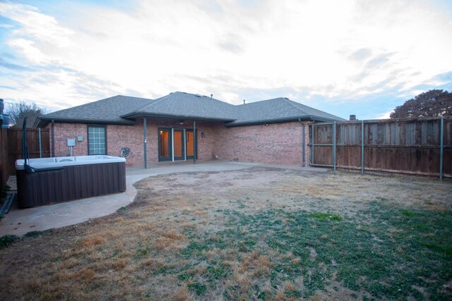 rear view of property with a hot tub and a patio