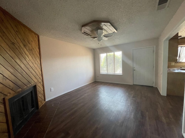 unfurnished living room featuring a brick fireplace, dark wood-type flooring, a textured ceiling, and ceiling fan