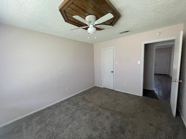 unfurnished bedroom featuring ceiling fan, a textured ceiling, and dark colored carpet