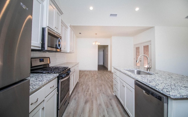 kitchen with tasteful backsplash, sink, light stone counters, and appliances with stainless steel finishes