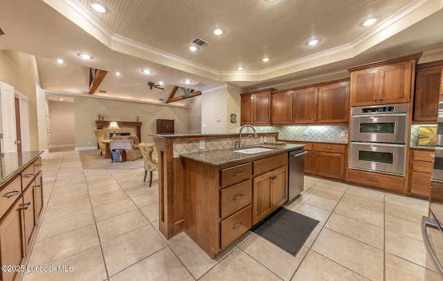 3914 101st St, Lubbock, TX 79423 - kitchen featuring a tray ceiling, stainless steel appliances, open floor plan, ornamental molding, and a kitchen bar