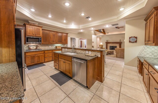 3914 101st St, Lubbock, TX 79423 - kitchen with stainless steel appliances, a raised ceiling, crown molding, backsplash, and a glass covered fireplace