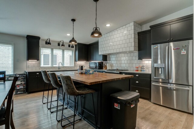 3711 128th St, Lubbock, TX 79423 - kitchen featuring stainless steel refrigerator with ice dispenser, butcher block countertops, dark cabinetry, a breakfast bar area, and a center island