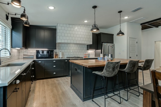 3711 128th St, Lubbock, TX 79423 - kitchen featuring butcher block countertops, stainless steel appliances, custom range hood, dark cabinets, and a kitchen island