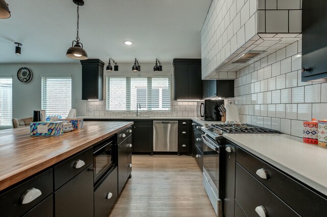 3711 128th St, Lubbock, TX 79423 - kitchen featuring butcher block counters, stainless steel appliances, dark cabinetry, tasteful backsplash, and recessed lighting