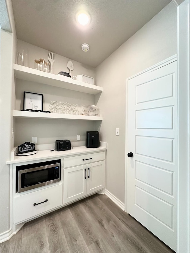 bar featuring white cabinets and light hardwood / wood-style floors