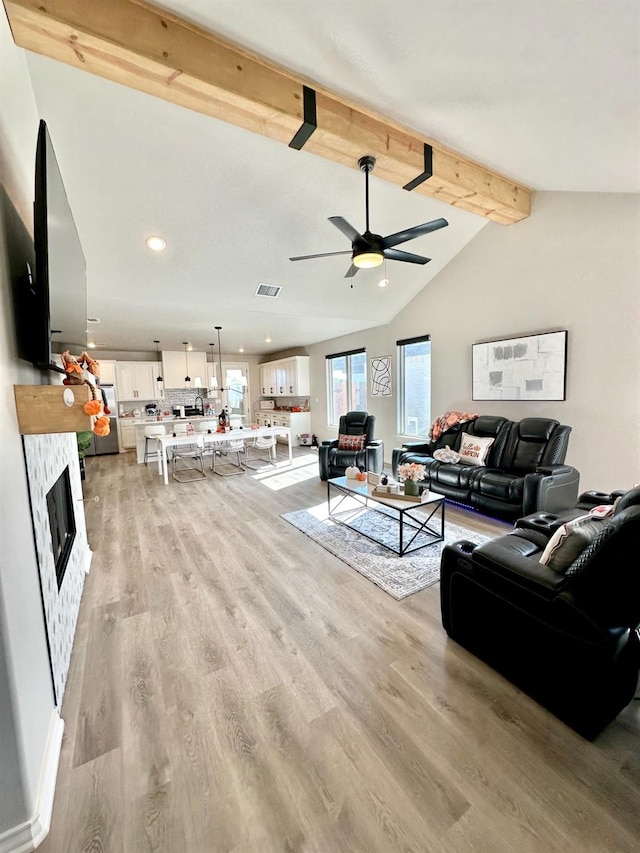 living room featuring lofted ceiling with beams, light hardwood / wood-style floors, and ceiling fan